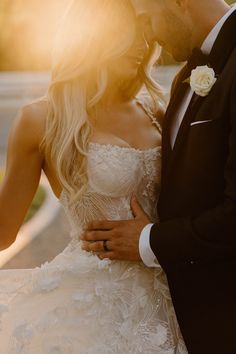 a bride and groom standing close together in front of the sun at their wedding day