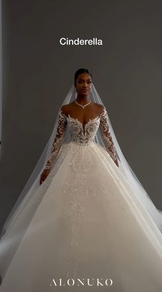 a woman wearing a wedding dress with long sleeves and a veil on her head, standing in front of a gray background