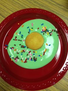 a red plate topped with a green frosted doughnut covered in sprinkles