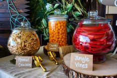 there are many different types of candies in glass jars on the table with place cards