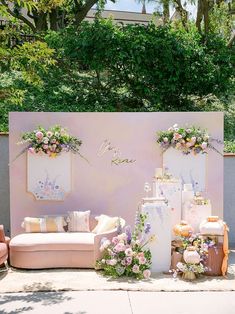 an outdoor seating area with flowers on the wall and couches in front of it