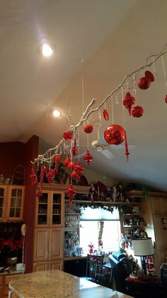 a kitchen with red ornaments hanging from the ceiling and lights on the ceiling above it