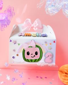 a pink and white box with a cute cartoon character on the front is surrounded by confetti