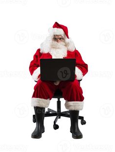 santa claus sitting on a chair with his legs crossed and holding a laptop computer in front of him