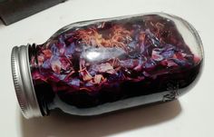 a jar filled with purple flowers sitting on top of a white counter next to a knife