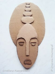 a cardboard cutout of a woman's face with stones on her head