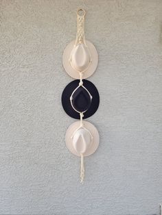 three hats hanging on a wall with chains attached to it's sides, one black and one white