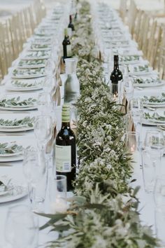 a long table is set with wine bottles and place settings