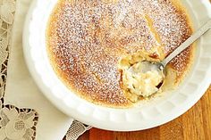 a white bowl filled with pudding on top of a wooden table next to a doily