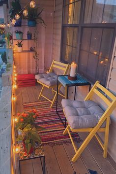 two yellow chairs sitting on top of a wooden deck next to a table with candles