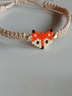 an orange and white beaded bracelet on a gray surface with a silver chain around it