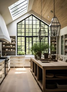 an open kitchen with lots of counter space and hanging lights over the island area, along with large windows