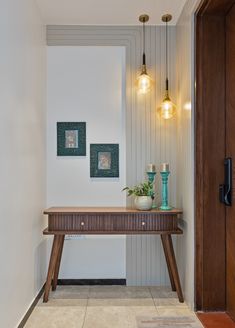 a wooden table sitting in the middle of a room next to a doorway with two lights hanging above it