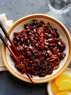 a bowl filled with noodles and chopsticks on top of a table