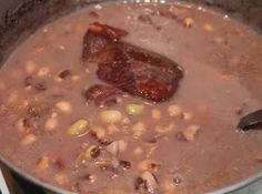 a pot filled with beans and meat on top of a stove