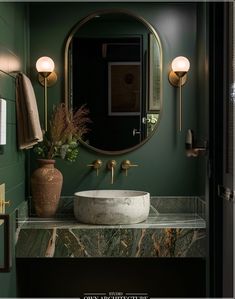 a bathroom with green walls and marble counter top, round mirror above the sink area