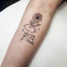 a woman's arm with a sunflower and clouds tattoo on the left forearm