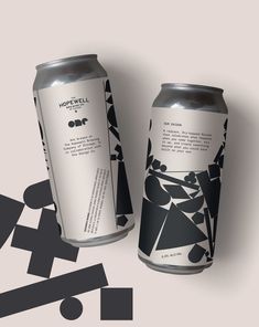 two cans of beer with black and white designs on them, next to each other