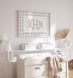 a baby's room with a white dresser and checkered wall hanging above it