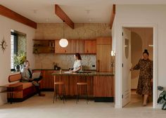 two women sitting at a kitchen counter in a house with wood paneling on the walls