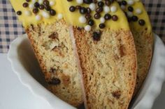 two slices of cake with yellow icing and chocolate chips on top in a white bowl