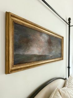 a painting hanging on the wall next to a bed with white sheets and pillowes