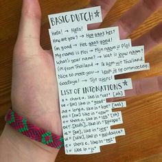 a person's hand holding a piece of paper with instructions for basic dutch words