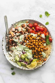 a white bowl filled with chickpeas, tomatoes, cucumber and avocado