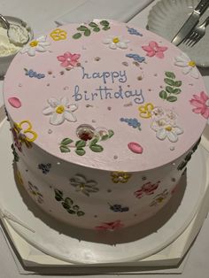 a birthday cake is decorated with flowers and the words happy birthday on it's side