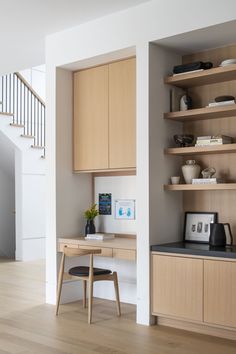 a wooden desk sitting under a stair case next to a wall mounted shelf filled with books