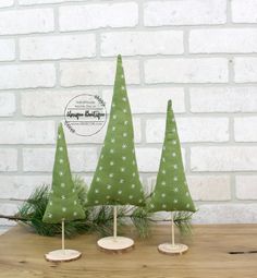 three small green christmas trees sitting on top of a wooden table