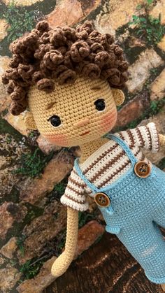 a crocheted doll with brown hair and blue overalls