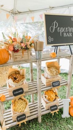 an outdoor popcorn bar with pumpkins and other snacks