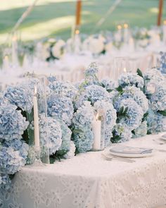 the table is set with blue flowers and candles