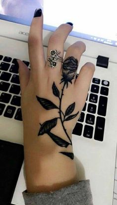 a woman's hand on top of a laptop computer with a rose tattooed on it