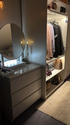 a white dresser sitting next to a mirror on top of a wooden cabinet in a room