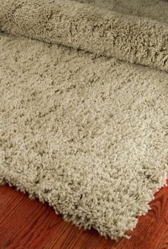 an area rug is laying on the floor next to a wooden floor with a brown and white color scheme