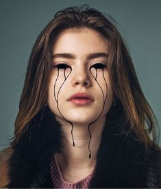 a woman with long hair and black lines on her face