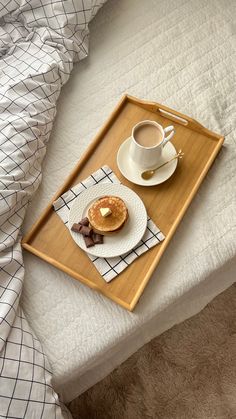 a tray with a cup of coffee and a donut on it sitting on a bed