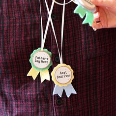 a person is holding two badges that say father's day hero and best dad ever