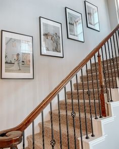 a staircase with pictures on the wall and wooden banisters in front of it