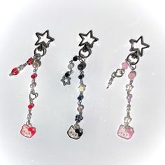 three pairs of earrings with charms attached to them