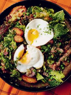 two fried eggs are on top of some broccoli and other vegetables in a skillet