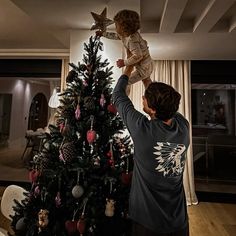 a man holding up a child on top of a christmas tree