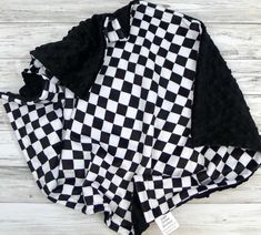 a black and white checkered shirt laying on top of a wooden floor