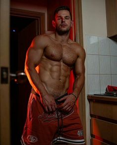 a shirtless man standing in a bathroom with his hands on his hips and looking at the camera