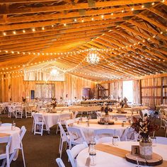 the inside of a barn with tables and chairs set up for an event or function