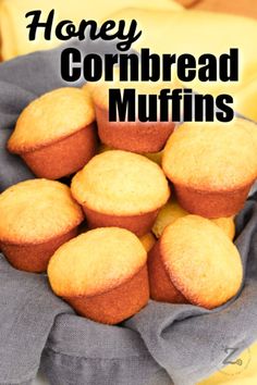 a bunch of muffins sitting on top of a cloth covered bowl with the words honey cornbread muffins