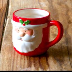 a red and white santa claus mug sitting on top of a wooden table