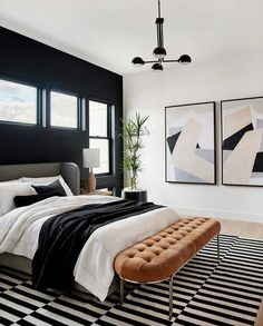 a black and white bedroom with a large bed in the middle, two paintings on the wall